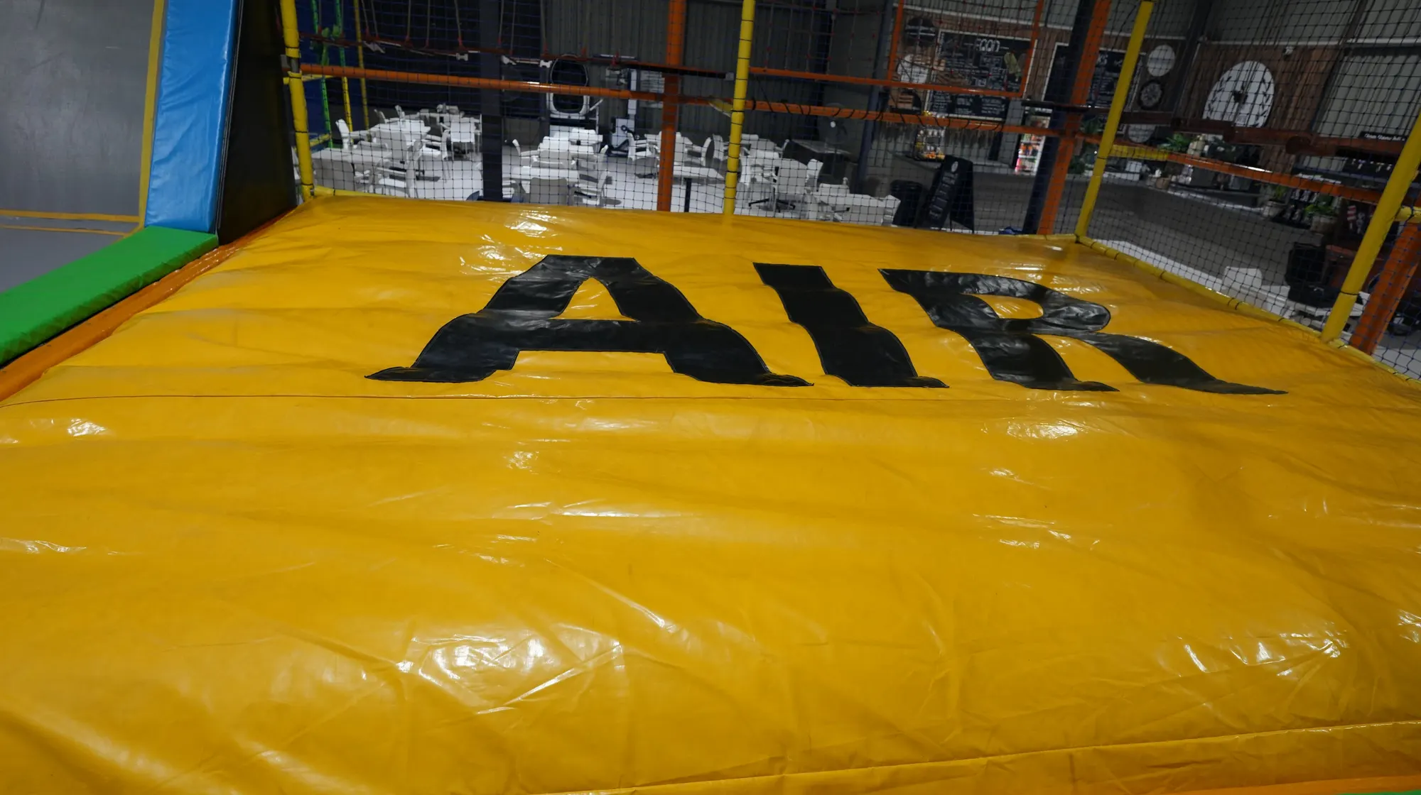 Yellow airbag marked AIR to bounce onto, with trampoline pads beside it at Jump Trampoline Park, Harare